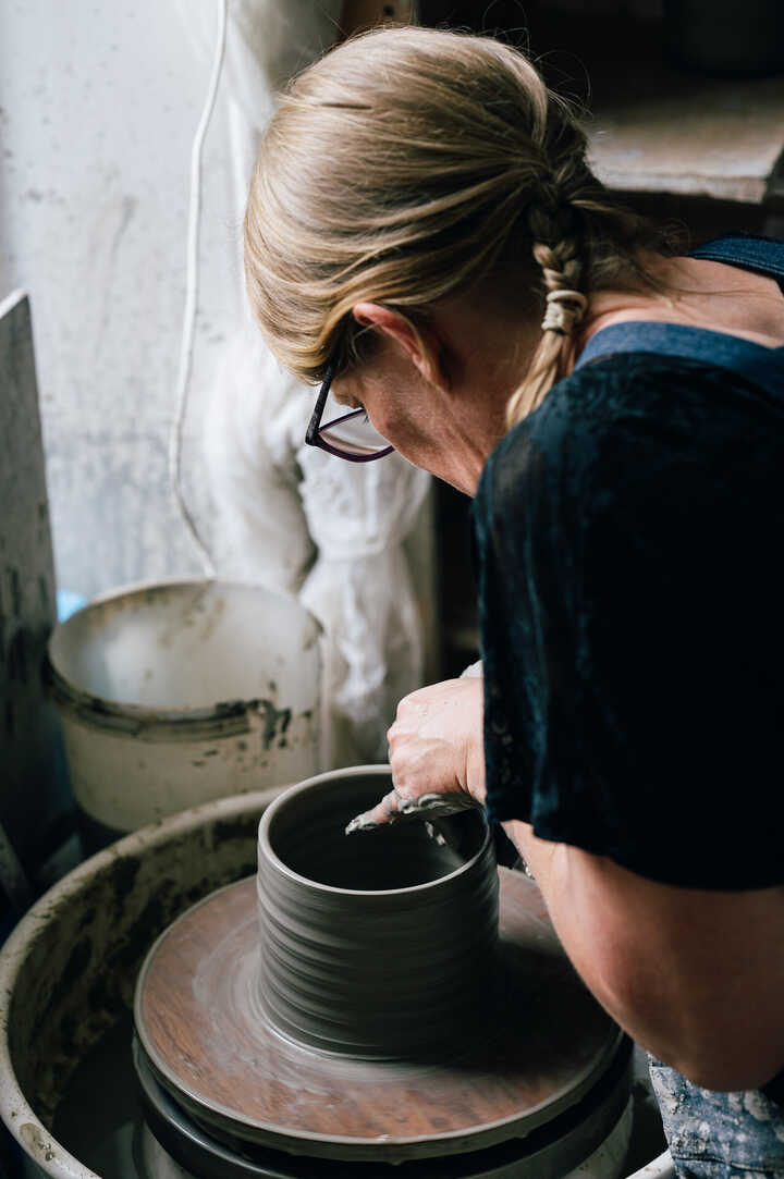 Potter throwing jug on pottery wheel