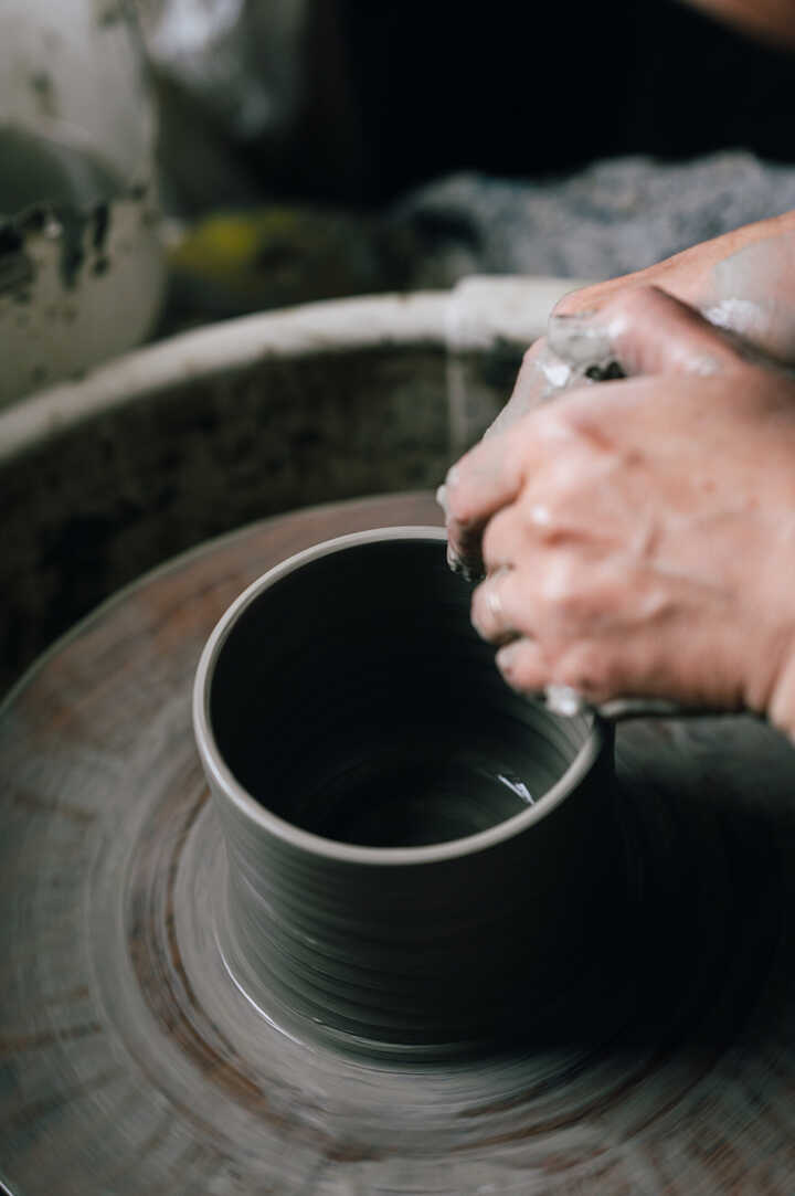 Potter throwing jug on pottery wheel